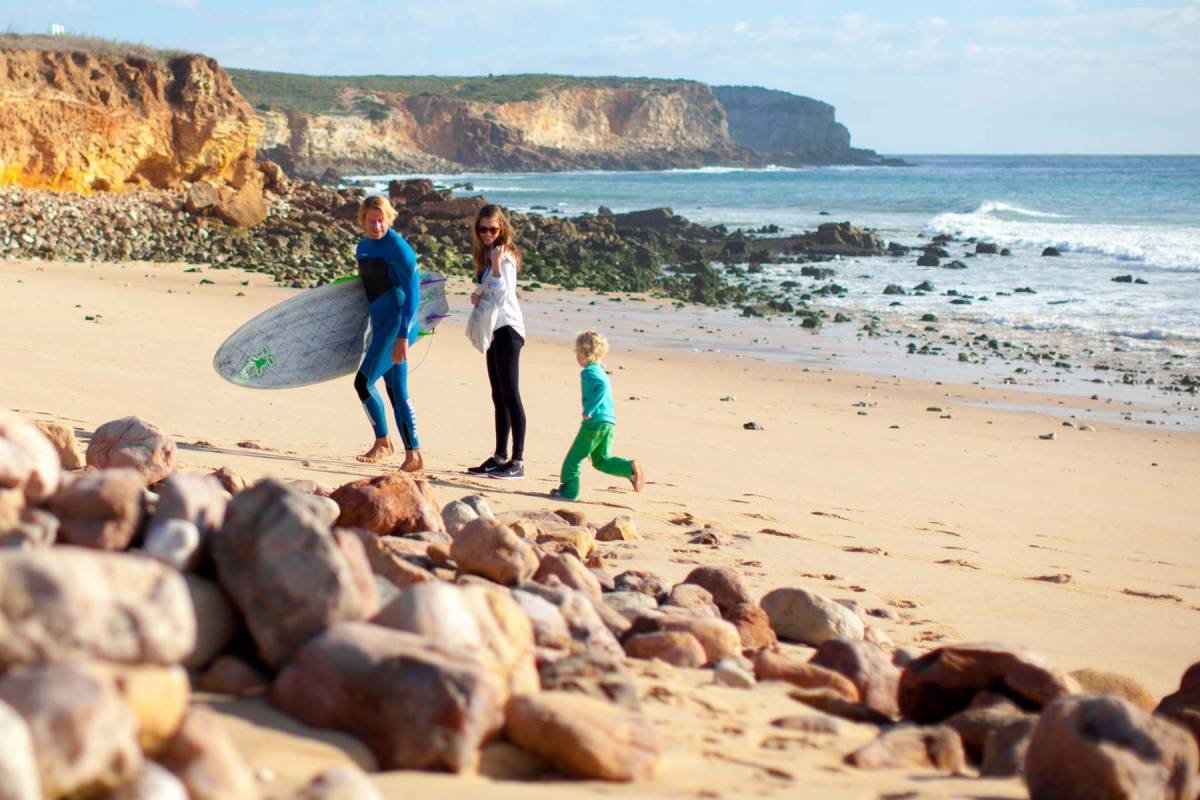 Ein Mann mit Surfbrett mit seiner Frau und seinem Sohn am Strand
