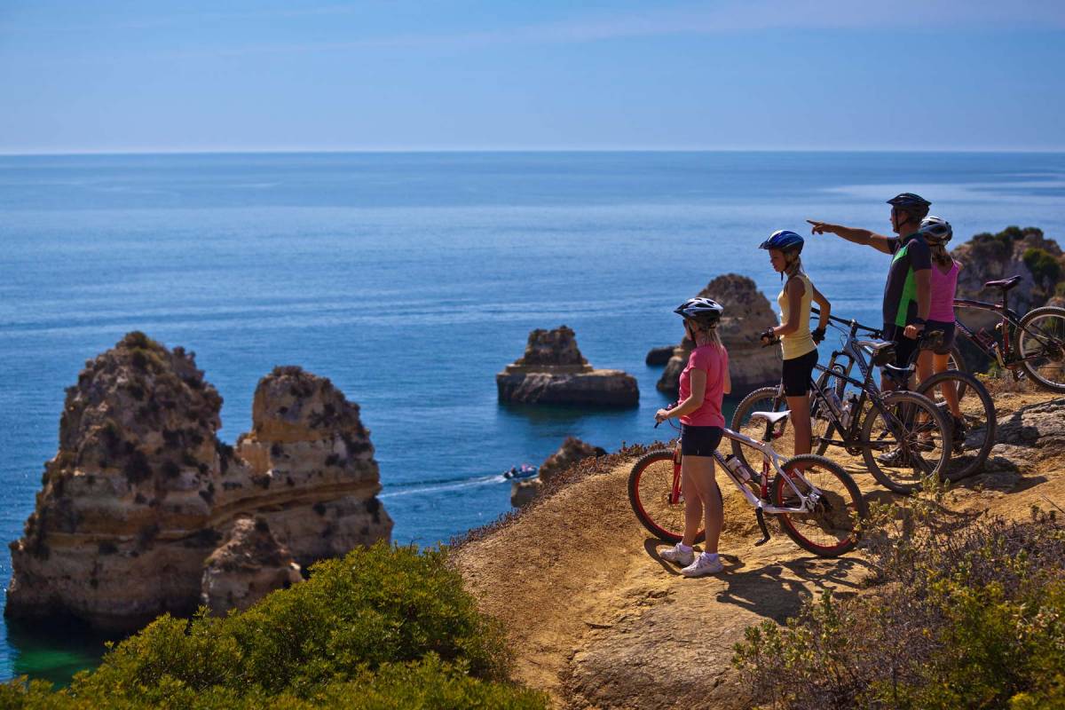 Eine Familie mit Fahrrädern blickt von einer Klippe auf das Meer
